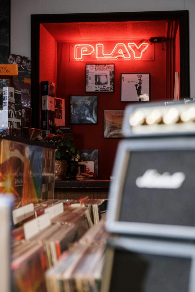 Picture of a vinyl music store showing display of music records with a red light spelling out Play.