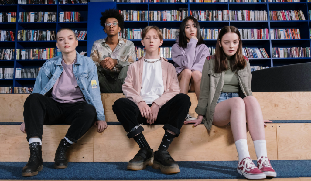 a group of teens sitting on a bench in a library